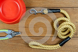 Pet leashes and plastic bowl and nail scissors on wooden table