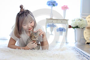 Pet Lover concept. Cat in the embrace of the woman lying on the wool carpet. Young Female lying in bed and holding her beautiful