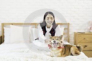 Pet Lover concept. The girl is smiling with the Shiba Inu dog on the bed in the bedroom. Shiba Inu is a Japanese dog that is