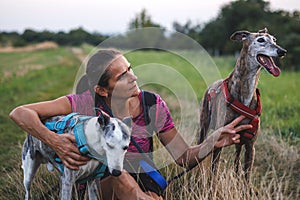 Pet owner or animal trainer doing obedience training with spanish greyhound and whippet