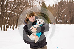 Pet owner, dog, and people concept - Young smiling caucasian man holding Jack Russell terrier outdoor in winter time.