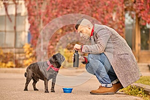 A pet owner pouring water for his friend to the bowl