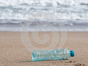 A PET plastic bottle left on the sandy beach. Plastic pollution environment concept