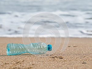 A PET plastic bottle left on the sandy beach. Plastic pollution environment concept