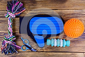 Pet slicker brushes, claw clipper and toys on a wooden background. Top view