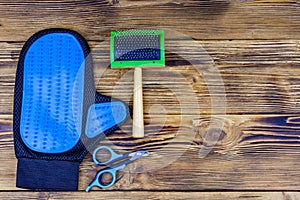 Pet slicker brushes and claw clipper on a wooden background. Top view