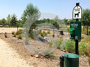 Pet Waste Station sign with bags and fenced field