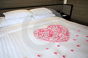 Petals of roses on a white honeymoon bed