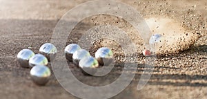 Petanque ball boules bowls on a dust floor, photo in impact. Game of petanque on the ground photo