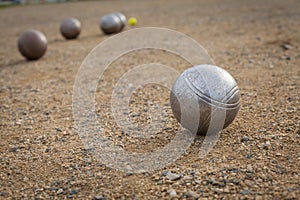 Petanque balls on a sandy pitch with other metal ball in the background