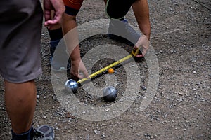 Petanque game, man measuring the distance of petanque ball in petanque field