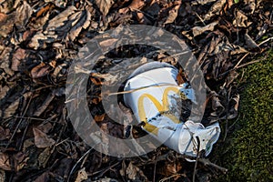 Empty disgarded MacDonalds Drink cup with platic lid lying as litter