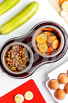 Petfood set with vegetables and eggs on kitchen table background top view