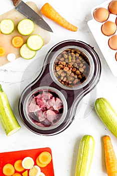 Petfood set with vegetables and meat on kitchen table background top view