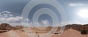 Petra ancient stone Qasr al-Bint gate and ruins with tiled roads sun and clouds sky