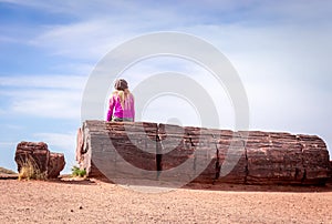 Petrified Forest National Park, AZ, USA - Girl Sitting on the Tree Trunk Fossil