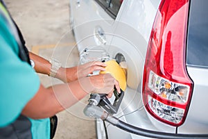 Petrol pump nozzle placed in silver car`s petrol tank ready to fill up. Shallow focus on nozzle.