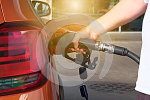Petrol station pump. Pumping gasoline fuel in orange car at a gas station. To fill orange car with fuel in petrol station.