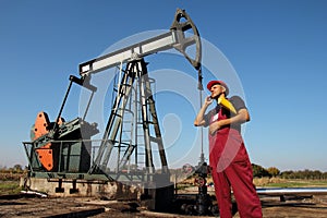 Petroleum Engineer Talking to Smartphone in Front of Oil Pump