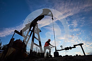 Petroleum operator using pump jack in oil field.