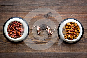 Pets accessories in home. Cat food in bowl, mouse toys on dark wooden background top view copy space
