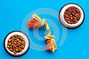 Pets accessories in home. Dog food in bowl and toys on blue background top view