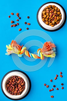 Pets accessories in home. Dog food in bowl and toys on blue background top view