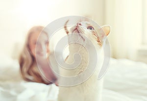 Happy young woman with cat in bed at home