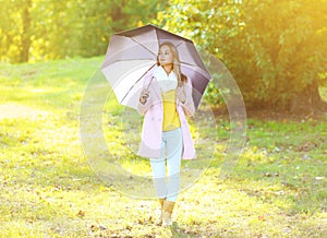 Petty sensual woman with umbrella in sunny autumn