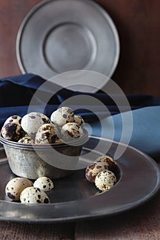 Pewter plates with quail eggs on table