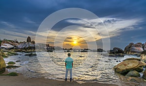 The lonely man watches the sunrise on a sandy beach