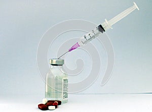 A PHARMA AND MEDICAL IMAGE CONTAINING AN INJECTION BEING FILLED THROUGH A GLASS VIAL AND WITH SOME TABLETS SURROUNDED