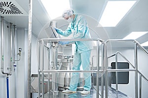 Pharmaceutical factory man worker in protective clothing operate production line in sterile working conditions