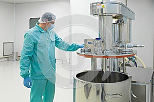 Pharmaceutical factory man worker in protective clothing working with control panel in sterile working conditions