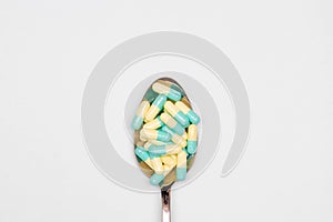 Pharmaceutical and health concept, Antibiotic capsules green yellow in spoon on white background