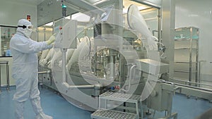 Pharmaceutical industry. Male factory worker inspecting quality of pills packaging in pharmaceutical factory. Automatic