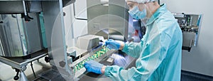 Pharmaceutical industry man worker in protective clothing operating production of tablets in sterile working conditions photo