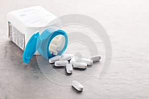 Pharmaceutical medicine tablets, pills, capsules, drugs on grey background in white and blue plastic jar. Pill bottle