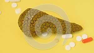 Pharmaceutical pills and capsules falling from above on anatomical shape of pancreas gland, symbolizing treatment of pancreas glan