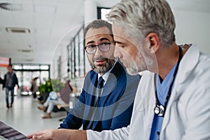 Pharmaceutical sales representative presenting new medication to doctor in medical building, holding box with medication