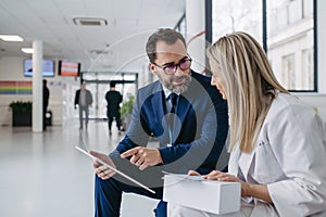 Pharmaceutical sales representative talking with doctor in clinic lobby. Ambitious male sales representative presenting