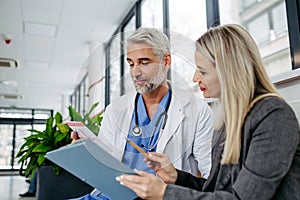 Pharmaceutical sales representative talking with doctor in medical building. Ambitious female medical rep presenting new