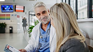 Pharmaceutical sales representative talking with doctor in modern clinic. Ambitious female medical rep presenting new