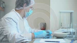 Pharmaceutical scientist worker weighing tablet pill on control scales. he writes down the numbers spbas