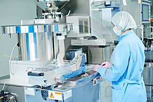 Pharmaceutics. Pharmaceutical worker operates blister packaging machine photo