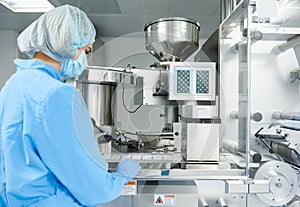 Pharmaceutics. Pharmaceutical worker operates blister packaging machine photo