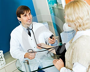 Pharmaceutist taking mature patients blood pressure using sphy