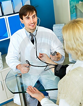 Pharmaceutist taking mature patients blood pressure using sphygmomanometer