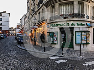 Pharmacie du Tertre at a street corner of Montmartre, Paris, France, on a summer evening.