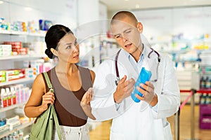 Pharmacist advises customer in harmacy, offers medicine for body care